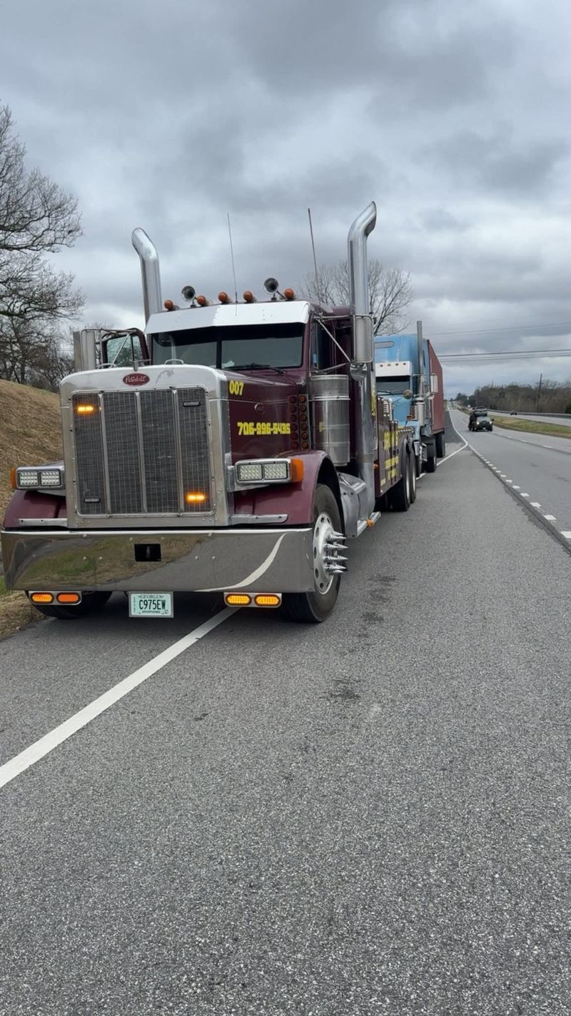 Brown's heavy wrecker stopped on a highway shoulder with a semi-truck behind it.