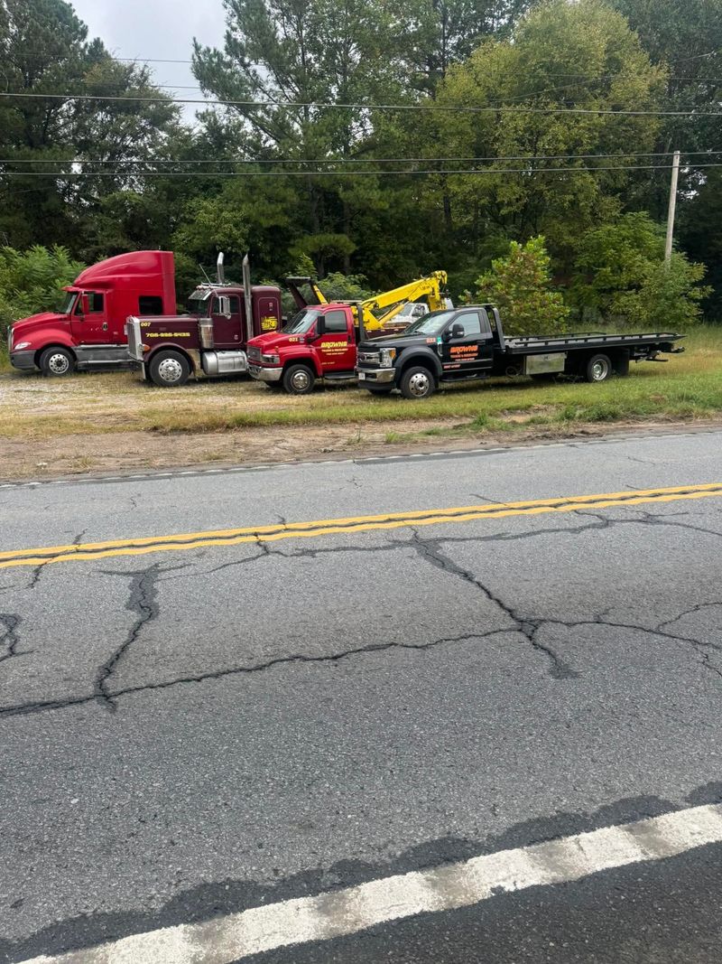 Trucks parked in a row beside a road, including Brown's wrecker and rollback.