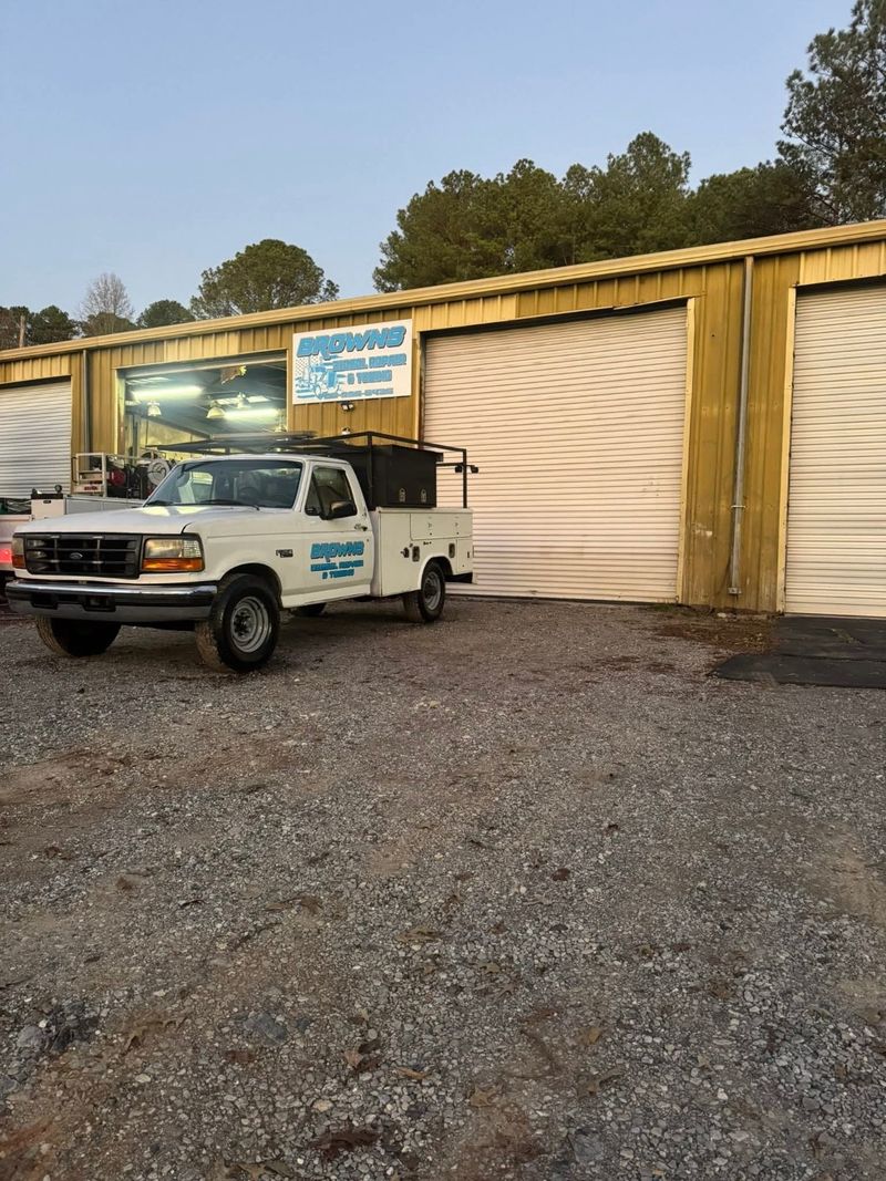 Brown's service truck parked outside the repair shop, with the business sign above the bay doors.