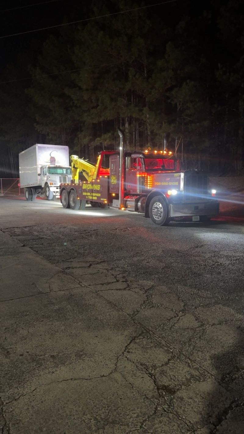 Brown's wrecker with a box truck behind it at night.